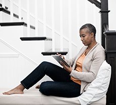 woman sitting on stairs looking at Veritas on a tablet